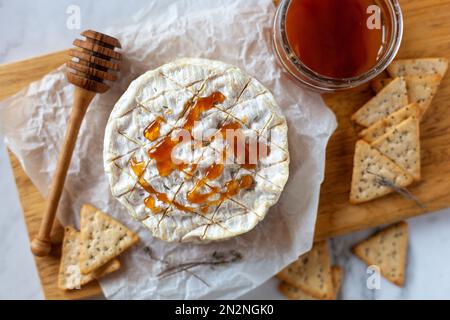 camembert formaggio francese morbido servito con miele liquido e cracker, vista dall'alto Foto Stock