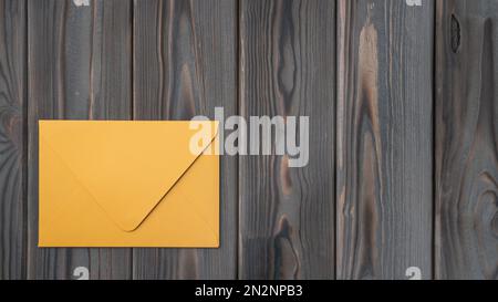 Piatto di busta chiusa gialla su tavolo di legno grigio. Corrispondenza, posta, ufficio postale, fisso, invito, documento, biglietto di auguri Foto Stock