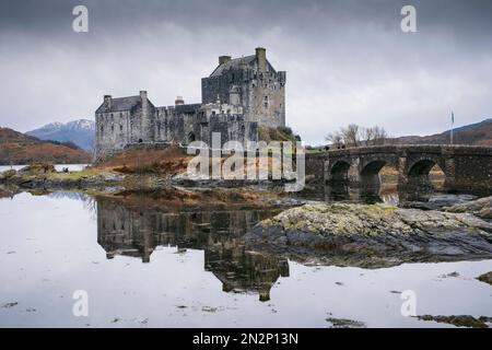 Scozia, Highlands, il castello medievale di Eilean Donan, Kyle of Lochalsh, vista invernale con lago Loch Alsh e montagne innevate Foto Stock