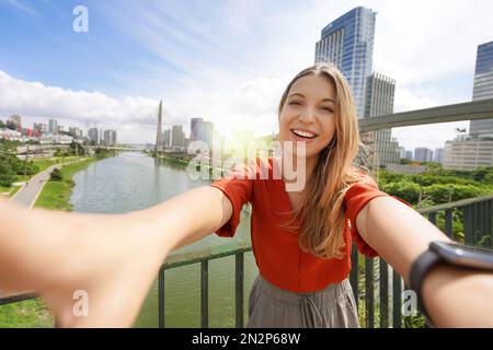 Felice ragazza sorridente prende autoritratto con Ponte Estaiada ponte e paesaggio urbano della metropoli di San Paolo, Brasile Foto Stock