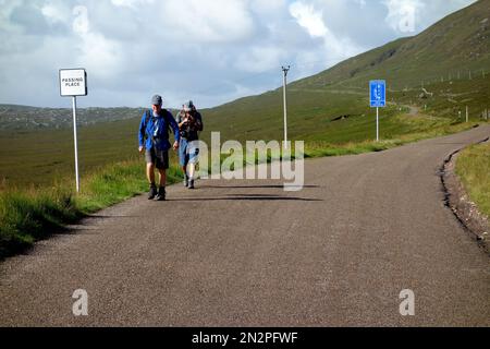 Due uomini a piedi sulla strada A838 vicino Carbreck (NC500) per il Corbetts Beinn Spionnaidh & Cranstackie nel Nord Ovest Sutherland, Highlands scozzesi, Regno Unito Foto Stock