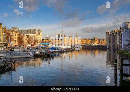 Guardando verso Amsterdam, stazione centrale dal canale Damrak Amsterdam Paesi Bassi. Foto Stock