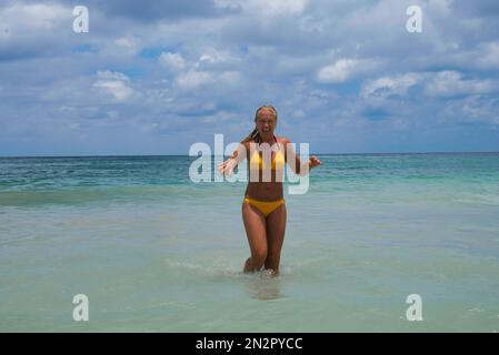 Donna sorridente in un bikini che cammina fuori dall'oceano, Beau Vallon Beach, Mahe Island, Seychelles Foto Stock