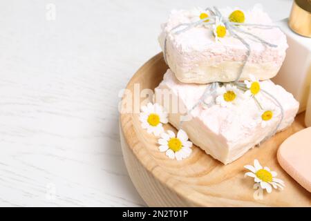 Fiori di camomilla e saponette su tavolo bianco, primo piano Foto Stock