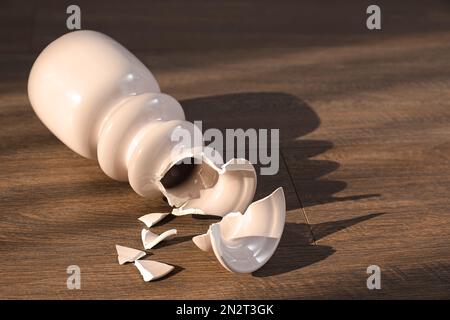 Vaso in ceramica rosa rotto su pavimento in legno Foto Stock