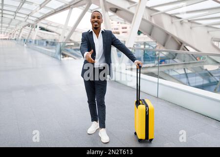 Indietro uomo d'affari allungando la mano per la stretta di mano alla macchina fotografica mentre in piedi in aeroporto Foto Stock