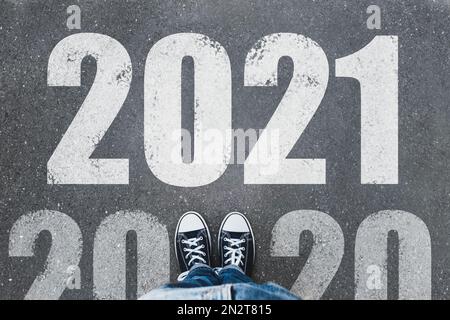 Inizia il nuovo anno con nuove idee e idee. 2021 numeri su strada asfaltata di fronte alla donna, vista dall'alto Foto Stock