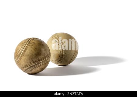 Un paio di palle retrò in pelle scottata con ombre in fusione su sfondo bianco Foto Stock