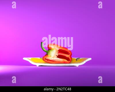 Primo piano di un peperone rosso su un piatto di ceramica Foto Stock