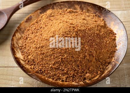 Ciotola di cocco con zucchero di palma dorato primo piano sul legno Foto Stock