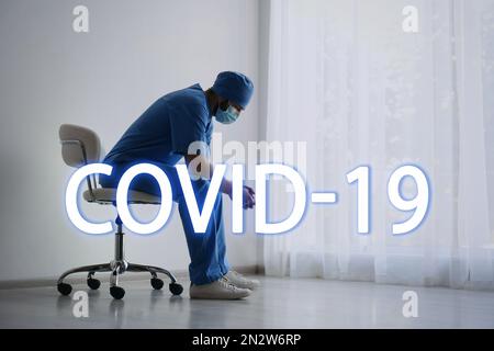 Medico sopraffatto stanco seduto sulla sedia in ospedale. Collasso del sistema medico durante la pandemia di coronavirus Foto Stock
