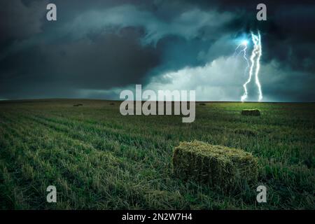 Splendida tempesta di temporali sul campo verde. Fulmini che colpiscono da un cielo nuvoloso e scuro Foto Stock