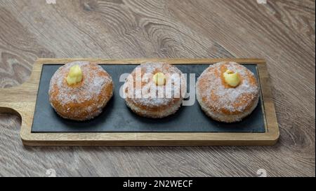 Ciambelle fritte fatte in casa riempite di crema e condite con un velo di zucchero Foto Stock