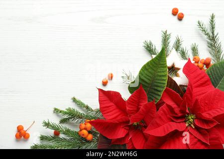 Composizione piatta con poinsettie (fiori di Natale tradizionali) e rami di abete su tavola di legno bianco. Spazio per il testo Foto Stock