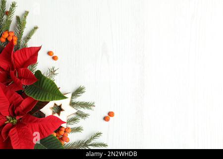 Composizione piatta con poinsettie (fiori di Natale tradizionali) e rami di abete su tavola di legno bianco. Spazio per il testo Foto Stock