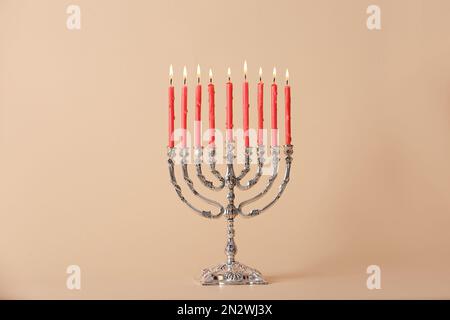 Menorah d'argento con candele accese su sfondo beige. Hanukkah celebrazione Foto Stock