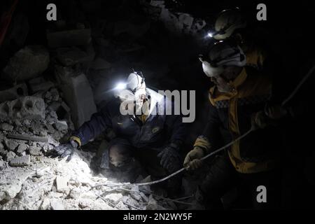 Harem, Siria. 07th Feb, 2023. I membri dei caschi bianchi lavorano per salvare le persone intrappolate sotto un edificio distrutto nella città di Harem in seguito al devastante terremoto che ha colpito il confine turco-siriano e ha lasciato più di 5000 persone morte. Credit: ANAS Alkharboutli/dpa/Alamy Live News Foto Stock