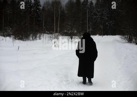 Donna cammina attraverso il parco in inverno. Il pensionato cammina in inverno. Dettagli della passeggiata nelle giornate fredde. Foto Stock