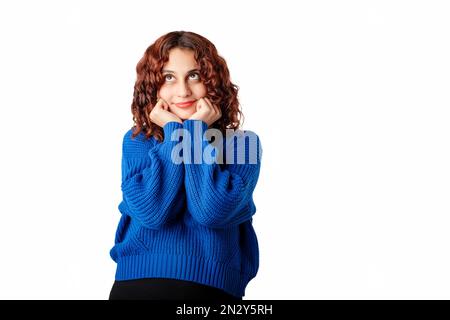 Bella donna che indossa maglia blu maglione in piedi isolato su sfondo bianco toccando mento con pugni, guarda l'angolo della copia vuota s Foto Stock