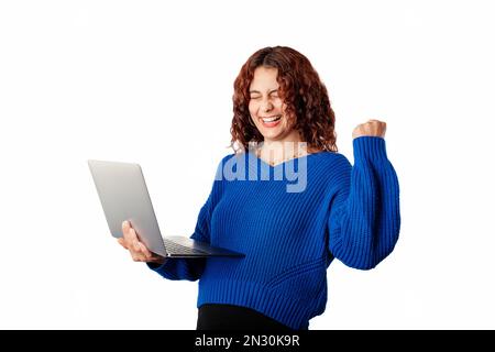 Cute donna caucasica che indossa pullover blu maglione isolato su sfondo bianco con gli occhi chiusi sta tenendo un portatile in mano ed è incredibile hap Foto Stock