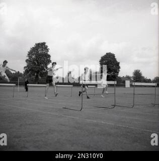 1950s, storico, fuori su un campo di sport in erba, ragazzi adolescenti che gareggiano in una gara di ostacoli, Inghilterra, Regno Unito. Foto Stock