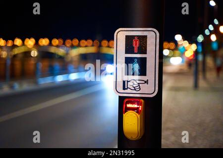 Foto notturna di un pulsante che accende un semaforo per un passaggio pedonale. Foto Stock