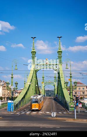 Scena al crocevia del terrapieno. Un tram attraversa un vecchio ponte sul fiume. Budapest, Ungheria - 08.25.2022 Foto Stock