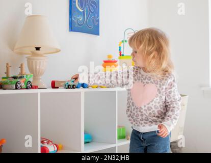 Bella bionda caucasica che gioca nella sua stanza con la macchina Foto Stock