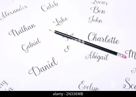 Matita ordinaria e diversi nomi dei bambini scritti su carta, primo piano Foto Stock