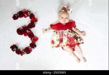 Bambina neonato in abito rosso. bambino di 3 mesi Foto Stock
