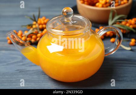 Delizioso tè alle buckthorn di mare e frutti di bosco freschi su un tavolo di legno blu Foto Stock