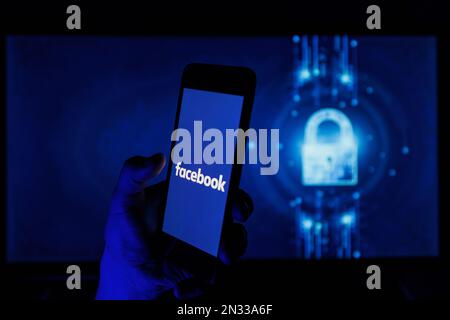 Vilnius, Lituania - 2022 febbraio 6: Logo aziendale di Facebook e Meta sugli schermi di smartphone e PC. Uomo che tiene in mano l'app facebook Foto Stock