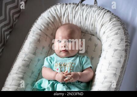 Ragazza carina caucasica di 4 mesi in una culla. Bambina. Neonato. Foto Stock