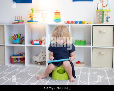 Bambino caucasico seduto su un vasino con la compressa Foto Stock