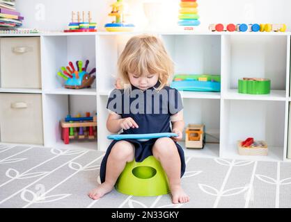 Bambino caucasico seduto su un vasino con la compressa Foto Stock