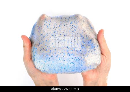 Gioco a mano con texture slime su sfondo bianco. Mano teen che tiene blu brillante slime con bolle, stretching la sostanza gooey. Ragazza adolescente Foto Stock