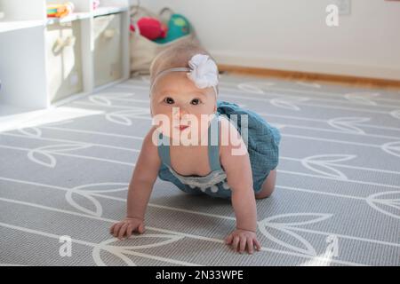 Cute piccola ragazza caucasica bambino imparando come strisciare Foto Stock