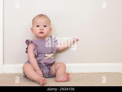 Ragazza caucasica cute bambino imparare come sedersi a 9 mese di età Foto Stock