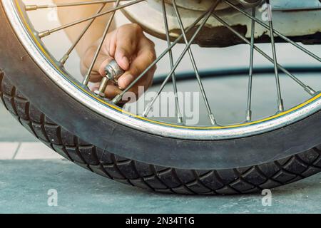 Mani di un uomo controllare la pressione del generatore di gas e gonfiare uno pneumatico su una motocicletta con un compressore pneumatico. Man controllo della pressione dell'aria e riempimento della pressione dei pneumatici Foto Stock