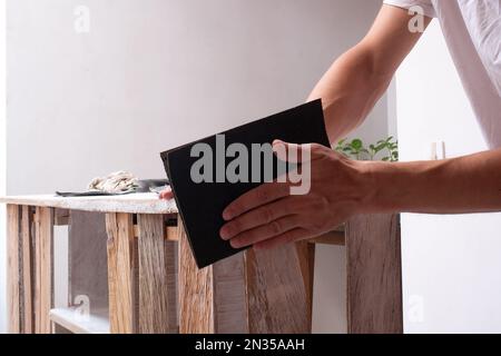 White Man Sands una scatola di legno utilizzando carta vetrata Foto Stock