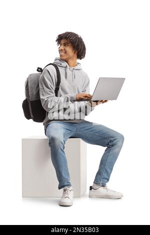 Studente afro-americano seduto con un computer portatile e guardando indietro isolato su sfondo bianco Foto Stock