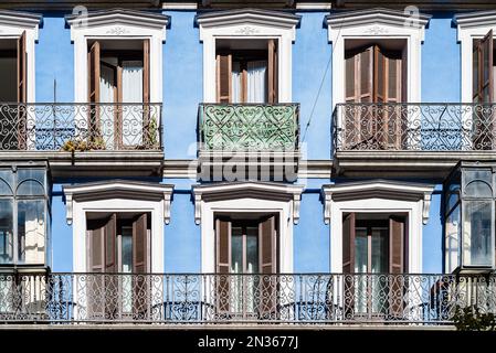 Vecchio edificio residenziale colorato nel centro di Madrid con balconi in ferro e facciata in stucco blu. Foto Stock