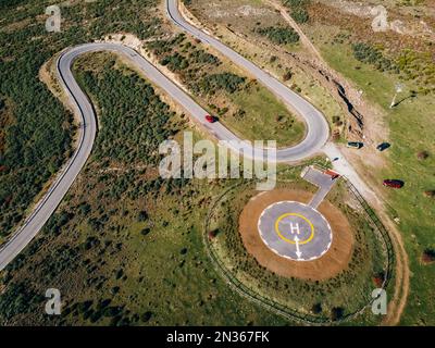 Vista aerea della strada tortuosa. Splendida scena mattutina di strada asfaltata. Eliporto per elicotteri di emergenza. Vista aerea dell'eliporto per l'elicottero di emergenza Foto Stock