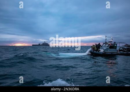 I marinai assegnati all'esplosivo Ordnance Disposal Group 2 recuperano una mongolfiera di sorveglianza ad alta quota al largo della costa di Myrtle Beach, South Carolina, mentre la nave portuale Harpers Ferry USS carter Hall (LSD 50) transita nelle vicinanze, il 5 febbraio 2023. EODGRU 2 è una parte fondamentale della forza di combattimento navale che elimina i pericoli esplosivi per fornire accesso alle aree negate; assicura il dominio sottomarino per la libertà di movimento; costruisce e promuove relazioni con partner di fiducia e protegge la patria. Sotto la guida del Presidente degli Stati Uniti e con il pieno sostegno Foto Stock