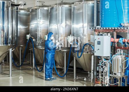 Ritratto completo del lavoratore in attrezzatura protettiva funzionamento serbatoi di stoccaggio attrezzature in fabbrica, spazio di copia Foto Stock