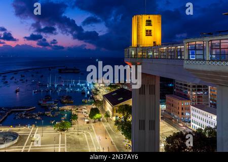 Facciata del famoso ascensore Lacerda illuminato di notte con città e barche in background a Salvador città, Bahia Foto Stock