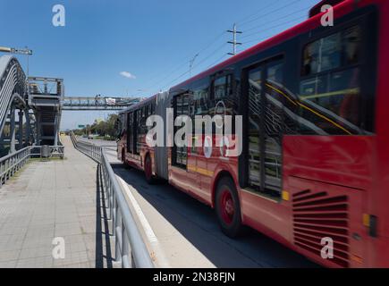 BOGOTA, COLOMBIA - Ponte Peatonale della stazione di Transmilenio con autobus rosso e cielo blu sullo sfondo Foto Stock