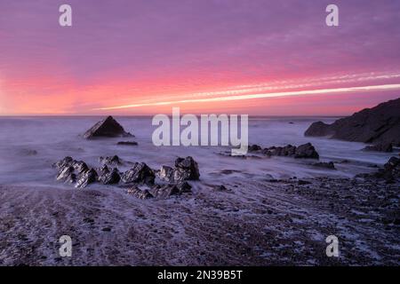 Sandymouth Bay, Bude, Cornwall, Regno Unito. 7th Feb, 2023. UK Weather: Un tramonto spettacolare sulla costa nord della Cornovaglia. Il cielo era pieno di colori fuochi d'artificio mentre il sole tramonta alla fine di una serata di febbraio luminosa, ma fredda. Credit: Celia McMahon/Alamy Live News Foto Stock