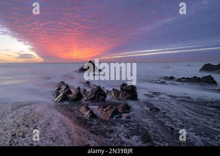 Sandymouth Bay, Bude, Cornwall, Regno Unito. 7th Feb, 2023. UK Weather: Un tramonto spettacolare sulla costa nord della Cornovaglia. Il cielo era pieno di colori fuochi d'artificio mentre il sole tramonta alla fine di una serata di febbraio luminosa, ma fredda. Credit: Celia McMahon/Alamy Live News Foto Stock