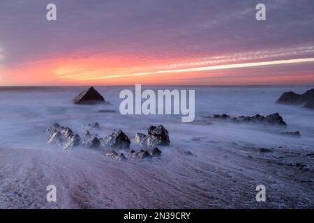 Sandymouth Bay, Bude, Cornwall, Regno Unito. 7th Feb, 2023. UK Weather: Un tramonto spettacolare sulla costa nord della Cornovaglia. Il cielo era pieno di colori fuochi d'artificio mentre il sole tramonta alla fine di una serata di febbraio luminosa, ma fredda. Credit: Celia McMahon/Alamy Live News Foto Stock